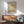 a living room with a wooden cabinet, a green armchair, and a wooden coffee table. Above the cabinet, there is a framed poster of an abstract art piece by Mark Rothko.