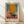 May include: Framed abstract art print in light wood frame leaning against white wall on natural wood floor. The artwork features bold geometric blocks of orange, teal blue, pink, and burgundy colors with painterly texture and loose brushwork. Artist name "MARK ROTHKO" appears in black text below the colorful composition on cream matting.