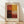 May include: Abstract art poster print in wooden frame leaning against white wall on light wood floor. Artwork features six rectangular color blocks in warm earth tones - burnt orange, golden yellow, deep burgundy, cream, and reddish-brown arranged in grid pattern. Text reads "Mark Rothko" below the image on cream-colored background with vintage texture.