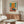May include: Abstract art poster with orange, teal, and pink color blocks in Mark Rothko style, displayed above wooden sideboard in modern living room with white curved chair, glass coffee table, and warm natural lighting streaming across polished floors.