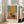 May include: Framed abstract art poster with orange, teal, and pink color blocks in Mark Rothko's style, displayed in bright living room corner next to beige sofa. White frame against cream walls with natural window light creating soft shadows on hardwood floors.