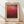 May include: Framed art print featuring abstract gradient from warm orange-red at top transitioning to deep burgundy and dark brown at bottom, displayed in light wood frame with cream matting against white wall on wooden floor with natural sunlight shadows