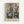 May include: Framed abstract artwork in muted teal, orange, and cream tones depicting geometric kitchen objects like coffee pots and bowls in a cubist style, displayed on a white wall in a light wooden frame. The composition features overlapping rectangular and curved forms with soft, painterly brushstrokes.