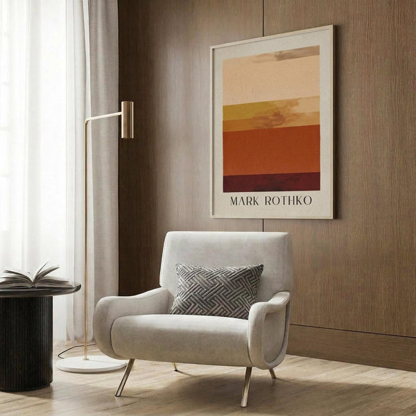 May include: Warm-toned abstract art print with horizontal color bands in cream, peach, orange, and burgundy displayed in light wooden frame on wood panel wall. Modern beige armchair with geometric patterned pillow sits below artwork. Gold floor lamp and dark round side table with open book complete the cozy reading nook scene with natural lighting from nearby window.