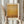 May include: Hands holding framed abstract art print with warm golden yellow and amber tones in minimalist style. Light wood frame against neutral beige curtain backdrop. Person wearing cream colored sweater with gathered cuffs also holds dried wheat stalks, creating soft natural styling scene.