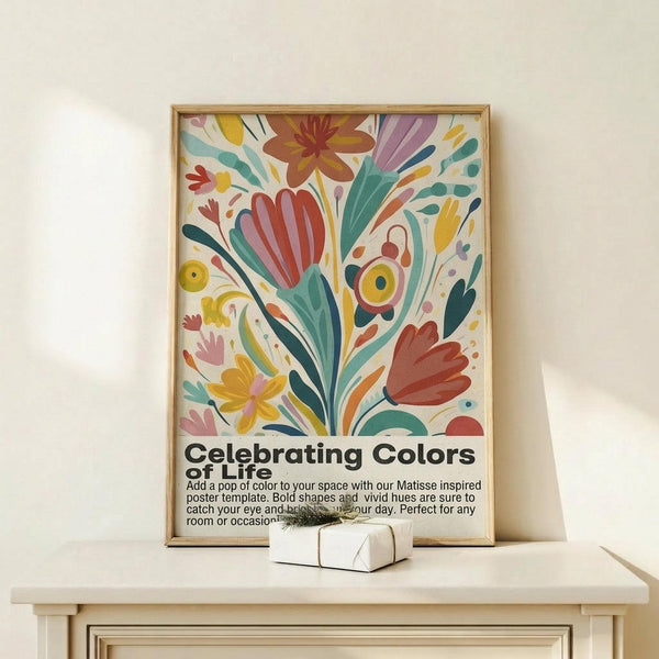 May include: Colorful abstract floral artwork in wooden frame leaning against white wall on light wood surface. Vibrant poster features botanical shapes in red, teal, yellow, purple, and orange with "Celebrating Colors of Life" text below. Small white gift box with twine sits in front. Matisse-inspired cut-out style with flowing organic forms and bold hues creates cheerful wall art display.