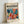 May include: Framed poster with "Matisse modernist" text and vibrant abstract botanical artwork featuring flowing leaves and organic shapes in teal, coral, orange, pink, and yellow colors. Light wood frame leans against white wall, showing colorful cut-out style design reminiscent of Matisse's paper collages. Bottom text reads "Embracing Colorful Freedom In the Spirit of Matisse" with exhibition dates at top.