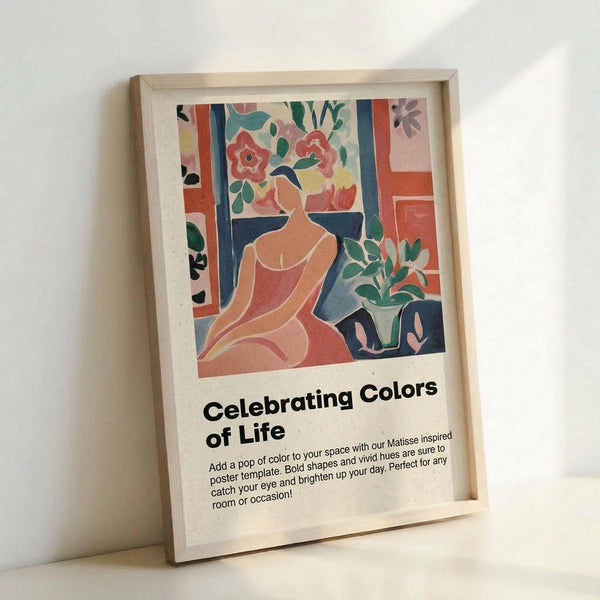 May include: Framed poster print leaning against white wall showing colorful Matisse-inspired artwork of woman in coral dress surrounded by flowers and plants in blues, greens, oranges and pinks. Light wood frame with white mat. Text below reads "Celebrating Colors of Life" with description about adding color to spaces.