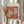 May include: Person holding framed Matisse-inspired art print featuring abstract cut-out paper shapes in warm autumn colors - orange, burgundy, yellow, and cream - with crosshatch patterns and organic flowing forms. Light wood frame against neutral curtained background, dried pampas grass visible on left side.