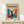 May include: Framed poster displayed on light wood console table against white wall. Poster features bold modernist design with silhouetted figure in dance pose, arms raised, surrounded by vibrant blue, orange, and yellow abstract shapes. Text reads "matisse modernist" with event details above. Small white gift box with twine sits nearby on table surface.
