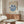 May include: Matisse exhibition poster with blue coral-like design on cream background, displayed in modern living room with wooden sideboard, white curved chair, glass coffee table, and contemporary lamp. Poster shows "BERGGRUEN & CIE" gallery text and Paris exhibition details from 1953.