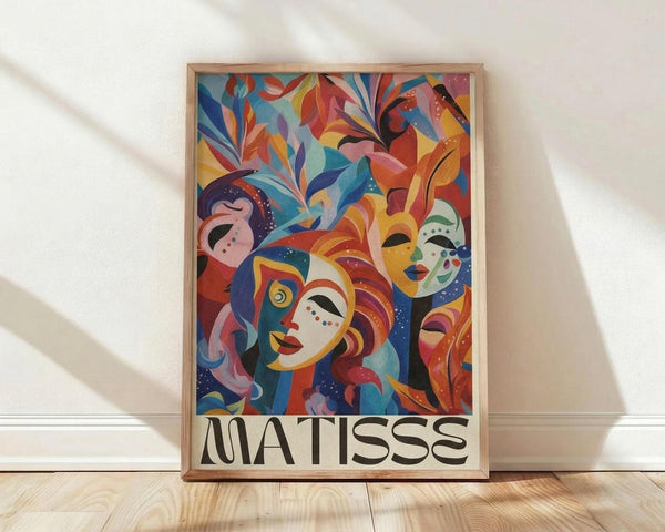 May include: Framed colorful abstract art poster leaning against white wall on light wood floor. Artwork features vibrant faces and masks in red, blue, yellow, orange, and pink with decorative foliage elements in Matisse-inspired style. Natural wood frame with clean lines. Soft natural lighting creates gentle shadows on textured white wall background.