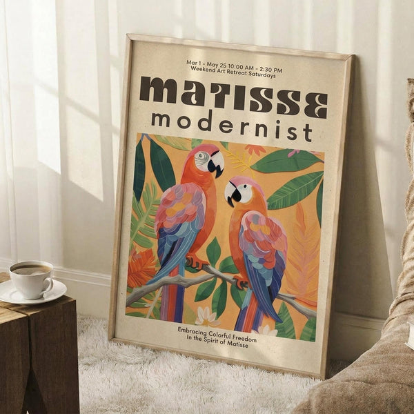 May include: Framed poster with colorful parrots perched on branches surrounded by tropical leaves, displayed against white paneled wall on textured white rug. Natural wood frame contains vintage-style art print with orange and yellow background. Small wooden side table with white coffee cup visible on left. Cozy home setting with beige throw blanket draped nearby.