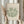 May include: Person in cream ruffled sleeves holding framed botanical art print featuring green coral-like shapes on beige background, with dried pampas grass in left hand, against soft white curtained window backdrop in minimalist neutral setting