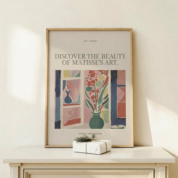 May include: Matisse-inspired art poster in natural wood frame displaying colorful interior scene with green vase of red flowers by window with blue frames, displayed on light wood surface next to small wrapped gift with twine and greenery sprig against cream wall
