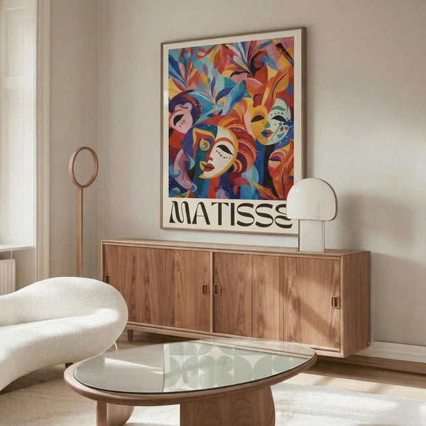 May include: Colorful abstract art poster featuring stylized faces and foliage in vibrant blues, reds, oranges, and yellows, displayed in thin gold frame above wooden mid-century modern credenza. Room shows white curved chair, glass oval coffee table, marble table lamp, and neutral walls with natural lighting.