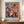 May include: Vibrant abstract poster featuring colorful stylized masks and flowing foliage in blues, oranges, reds, and yellows with "MATISSE" text at bottom, displayed in thin brown frame on wooden sideboard next to white ceramic vase and stacked books in modern room with cream walls and white molding