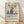 May include: Framed poster with Matisse-inspired still life artwork featuring colorful fruit and vases in blue, yellow, red and green against cream background, displayed leaning against white wall on light wood floor with natural window light creating soft shadows