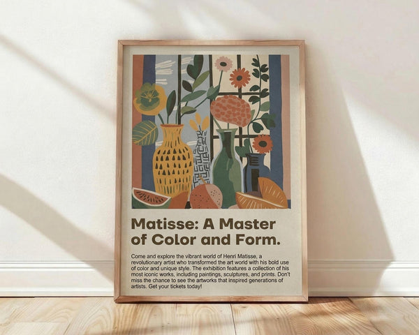 May include: Framed poster with colorful still life artwork featuring vases with flowers, fruit slices, and geometric shapes in warm oranges, greens, and blues. Bold text below reads "Matisse: A Master of Color and Form" with exhibition description. Light wood frame rests against white wall on light wooden floor with soft natural lighting creating diagonal shadows.