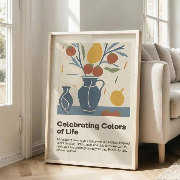 May include: Framed abstract art print featuring colorful still life with blue ceramic vases, orange and red fruits, yellow lemon, and botanical elements in Matisse-inspired style. Light wood frame leans against white wall next to beige sofa in bright, minimalist living room with large windows and natural light.