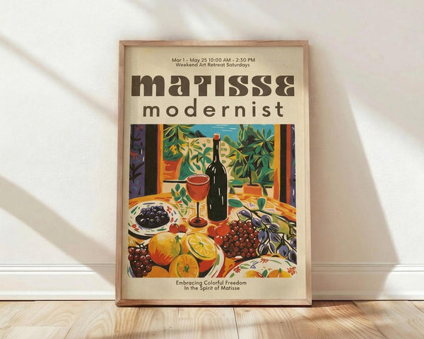May include: Framed poster with cream background displaying colorful still life artwork featuring wine bottle, red wine glass, fruits including oranges and grapes, leafy plants, and decorative objects in vibrant modernist style. Brown wooden frame sits on light wood floor against white wall with soft natural lighting creating diagonal shadows across the scene.