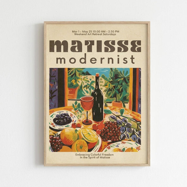 May include: Framed vintage-style poster featuring a colorful still life with wine bottle, glass, fruits including oranges and grapes, potted plants, and bowl of olives in bold, flat modernist art style with vibrant greens, oranges, and purples against cream background, displayed on white wall in light wood frame.