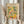 May include: Person in beige ruffled sleeves holding framed botanical poster print featuring colorful citrus fruits, leaves, and bottles in Matisse-inspired cut-out style with yellows, greens, pinks, and oranges on cream background in light wooden frame, with dried pampas grass visible beside neutral curtains.