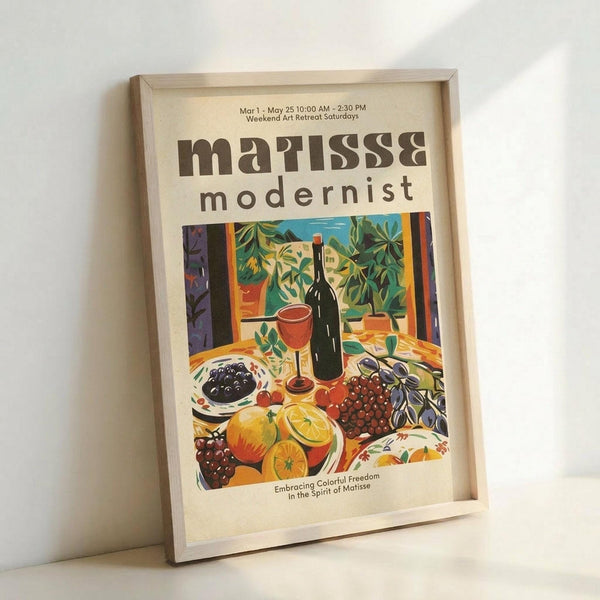 May include: Framed vintage-style modernist art poster featuring colorful still life scene with wine bottle, red wine glass, fruit including oranges and grapes, plants in terracotta pots, and bowl of olives. Bold text reads "matisse modernist" with exhibition details. Vibrant colors include greens, oranges, reds, and purples in fauve painting style. Light wooden frame displayed against white wall.