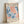 May include: Framed vintage Matisse exhibition poster leaning against white wall. Features abstract coral and blue organic shapes resembling seaweed or leaves on cream background. Text reads "MATISSE PAPIERS DÉCOUPÉS" at top and "BERGGRUEN & CIE" with Paris exhibition details at bottom. Natural wood frame with visible grain texture.