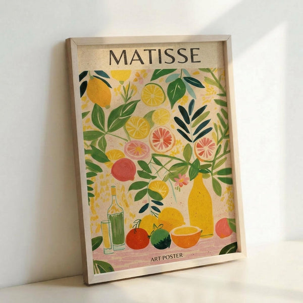 May include: Framed art poster with Matisse-inspired design featuring colorful citrus fruits, green foliage, and bottles arranged in still life composition. Bright yellows, oranges, greens and coral colors on cream background. Light wood frame displayed against white wall, showing natural lighting and shadows.