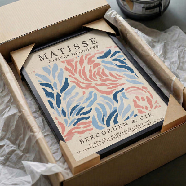 a framed poster of the painting "Matsisse Papiers Découpes" by the artist Berg Gruen, which is a decorative paper with a floral pattern. The poster is placed in a cardboard box, and there is a clear plastic wrapping around it.