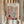 May include: Person in cream sweater holding framed Matisse-inspired art print featuring colorful botanical illustrations arranged in window pane layout. Artwork shows plants, leaves, and vase in warm orange, blue, green, and pink tones against cream background. Dried wheat stems visible beside figure with soft beige curtains in background.