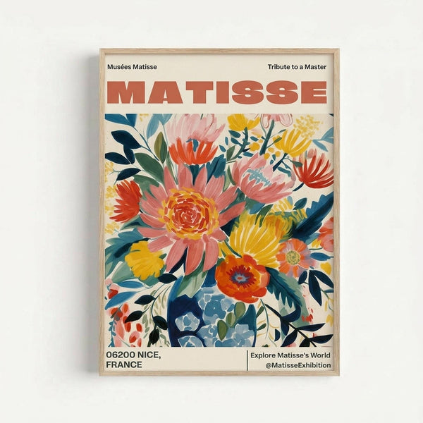 A colorful exhibition poster featuring vibrant painted flowers in coral, yellow, blue and green tones arranged in a loose bouquet style. The artwork displays "MATISSE" in large red letters at the top, with "Musées Matisse" and "Tribute to a Master" as headers. Bottom text shows "06200 NICE, FRANCE" and "Explore Matisse's World @MatisseExhibition". The poster is displayed in a light wood frame against a white wall.