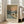 May include: Framed poster print of Monet's winter landscape with sailboat on water, bare tree in foreground, and pale sun in cloudy sky. Light wood frame leaning against white wall next to beige armchair in bright living room with large windows.
