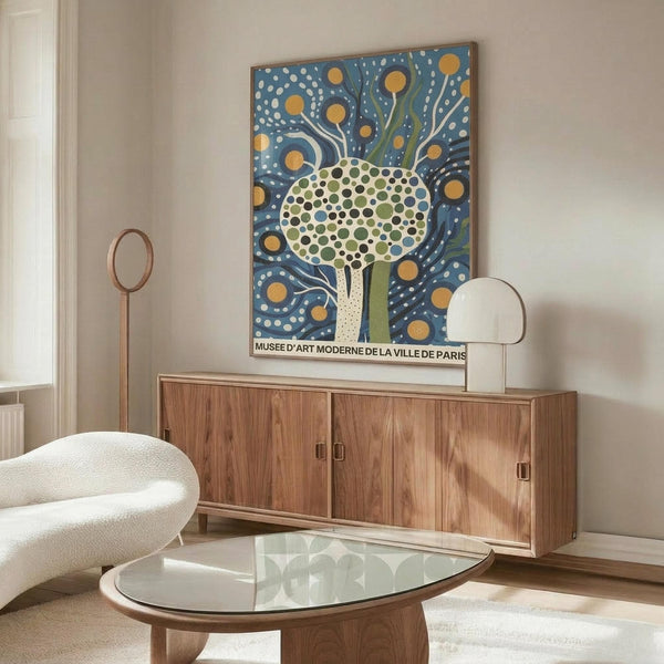 May include: Modern art poster featuring a stylized tree with circular dotted foliage in green tones against a blue background with white dots and golden yellow circles, displayed above a mid-century walnut credenza in a contemporary living room with white sculptural chair and glass coffee table.