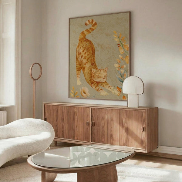May include: Orange tabby cat artwork hanging above wooden sideboard in modern living room with white curved chair, glass coffee table, and floor lamp. The poster shows a stretching orange cat with floral elements on neutral background in wooden frame.