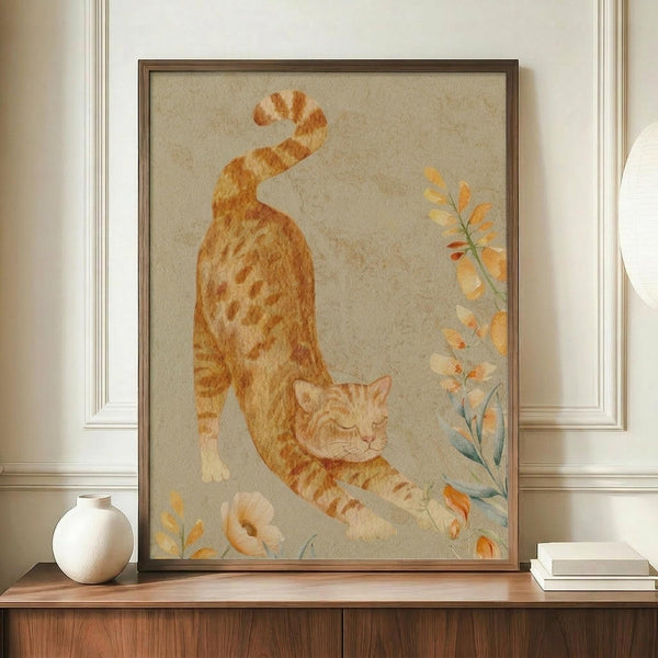 May include: Framed watercolor illustration of an orange tabby cat stretching with arched back, surrounded by delicate botanical elements in soft peach and sage green tones. The artwork is displayed on a wooden sideboard alongside a cream ceramic vase and stacked books against white wainscoting in a warm, neutral-toned room setting.