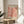 May include: Framed art print with "MATISSE" and "PAPIERS DÉCOUPÉS" text above and below coral pink abstract cut-out pattern on cream background, displayed on round wooden side table next to beige upholstered chair with plant leaves visible in soft natural lighting against white wall.