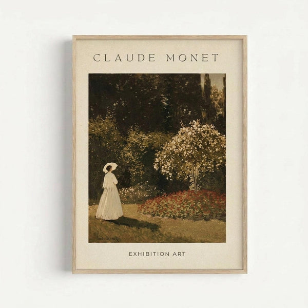 May include: Framed Claude Monet exhibition poster print hanging on white wall. Shows sepia-toned garden scene with woman in long white dress holding parasol, standing near flowering trees and colorful flower bed. Light wood frame with cream matting displays "CLAUDE MONET" and "EXHIBITION ART" text above and below the artwork.