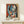 May include: Framed Picasso-style cubist artwork showing abstract female figure with geometric blue, red, and white shapes, displayed on light wood surface beside small wrapped gift. The poster features bold colors and angular forms typical of modernist art, set in thin natural wood frame against neutral wall.