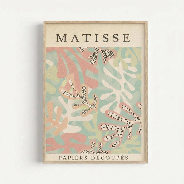 Framed art print featuring abstract cut-out paper shapes in soft pastel colors including coral pink, sage green, cream, and pale yellow. The composition includes organic flowing forms and geometric patterns with crosshatched textures and dotted details scattered throughout. Text reads "MATISSE" at top and "PAPIERS DÉCOUPÉS" at bottom on cream background. Natural wood frame against white wall.