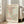 May include: Framed art print in light wood frame leaning against white wall next to beige upholstered sofa. Poster features abstract cut-out style shapes in soft pastels - coral pink, sage green, cream, and yellow - with black crosshatch and dotted patterns. Text reads "MATISSE" at top and "PAPIERS DÉCOUPÉS" at bottom on cream background. Bright natural light streams through tall windows in modern living room setting.