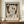 May include: Framed Paul Klee exhibition poster featuring abstract figure with angular white face, dark eye holes, and crescent moon against mottled brown background. Text reads "Exhibition Art - 1939" and "Angel Applicant - The Met Museum" with artist name below. Brown wooden frame sits on mid-century walnut credenza alongside white ceramic vase and stacked books in neutral-toned room with white walls and crown molding.