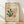 May include: Framed art print in light wood frame displaying abstract cut-out shapes in orange, green, and beige on cream background with French text. Print features organic coral-like forms and flowing botanical elements. Frame sits on light wood floor against white wall with soft natural lighting creating diagonal shadows.
