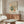 May include: Matisse-inspired botanical art print with orange and green abstract leaf shapes on cream background, displayed above walnut credenza in modern living room with white curved chair, glass coffee table, and soft natural lighting