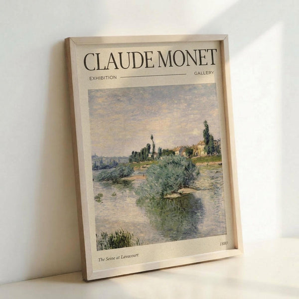 May include: Framed poster print of Claude Monet's impressionist landscape painting showing a winding river with lush green vegetation and trees along the banks under a soft cloudy sky. The artwork is displayed in a light wooden frame with cream matting that includes "CLAUDE MONET EXHIBITION GALLERY" text at top and "The Seine at Lavacourt 1880" at bottom. The frame leans against a white wall, casting a gentle shadow.