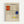 Framed poster featuring a geometric abstract composition with a grid of black lines on cream background. Two red rectangles in the upper left, one blue square on the right side, and one small yellow rectangle near the bottom center. The artwork has a sketchy, hand-drawn quality with visible pencil marks. Displayed in a light wooden frame against a white wall.