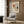 May include: Framed Piet Mondrian abstract composition study print with geometric grid and red, blue, and yellow color blocks, displayed on wood-paneled wall above beige upholstered chair with patterned throw pillow, alongside brass floor lamp and small side table with open book.