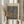 May include: Person in beige ruffled sleeves holding framed Paul Klee art print featuring abstract blue and brown stone-like shapes on warm background. Natural pampas grass stems visible beside frame. Soft window lighting creates neutral, minimalist styling against light curtains.