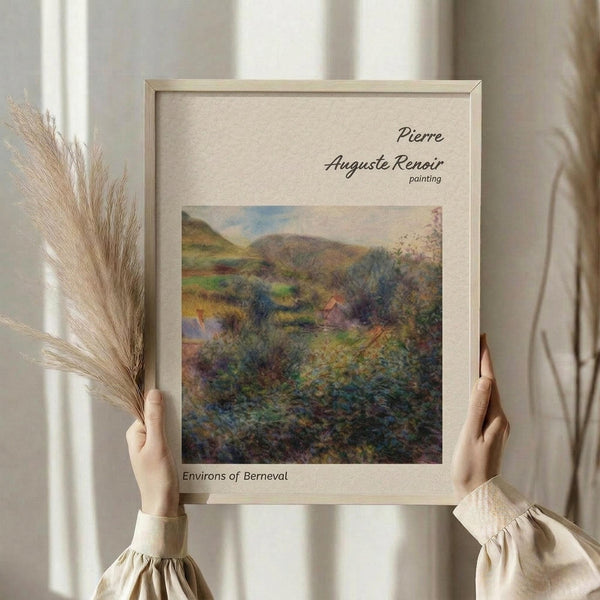 May include: Hands holding a framed impressionist landscape painting showing rolling hills, trees, and houses in soft greens, blues, and earth tones. Light wooden frame with cream matting displays the artwork against white curtains. Person wears cream ruffle-sleeved top and holds dried wheat stems, creating a minimalist aesthetic room scene.